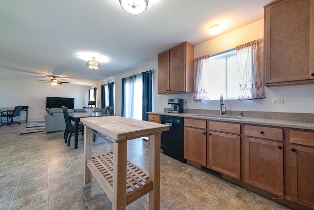 kitchen featuring dishwasher, a sink, a ceiling fan, stone finish floor, and brown cabinets