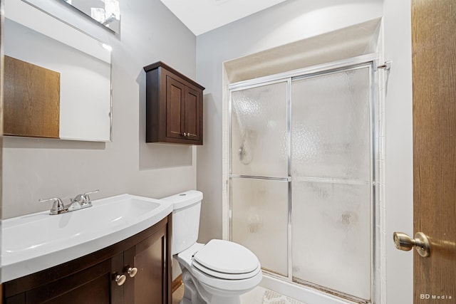 bathroom featuring toilet, a shower stall, and vanity
