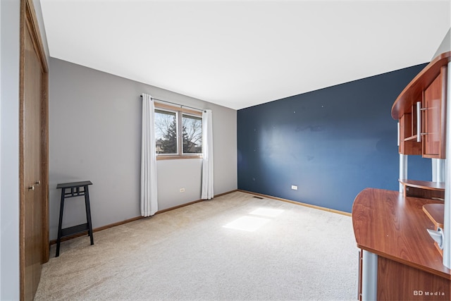 unfurnished office featuring light carpet and baseboards