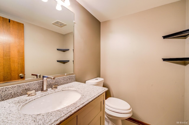 bathroom featuring visible vents, toilet, and vanity
