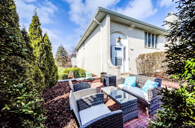 rear view of house with outdoor lounge area, a patio area, and brick siding