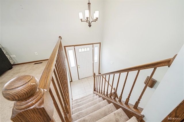 stairway featuring visible vents, baseboards, a chandelier, and a towering ceiling