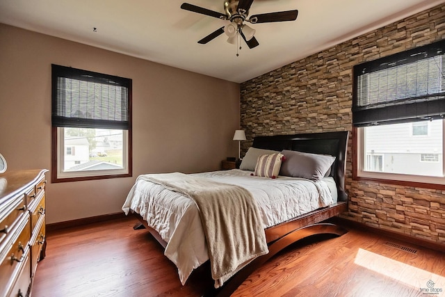 bedroom with visible vents, multiple windows, and wood finished floors
