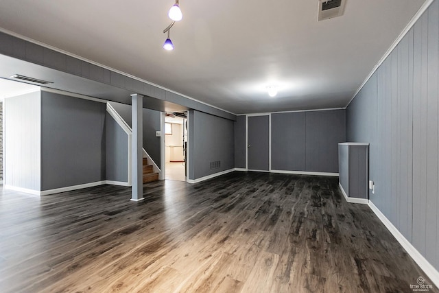 finished basement with dark wood-type flooring, visible vents, and stairway
