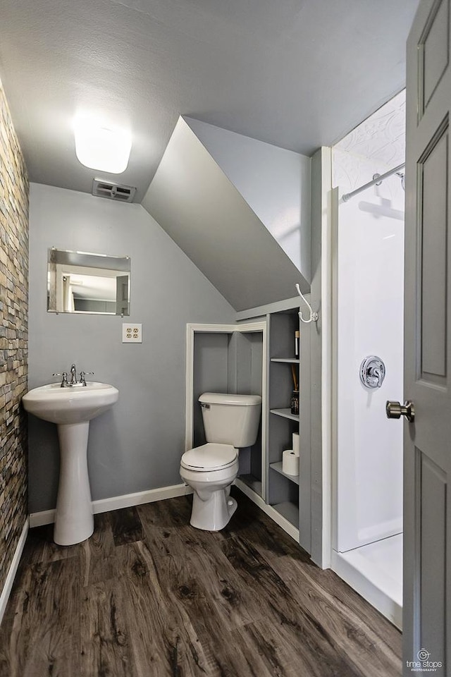 bathroom featuring visible vents, toilet, a shower, wood finished floors, and lofted ceiling