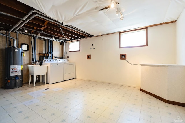 basement with water heater, separate washer and dryer, baseboards, light floors, and a sink