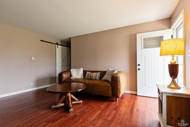 living room featuring a barn door, baseboards, and wood finished floors