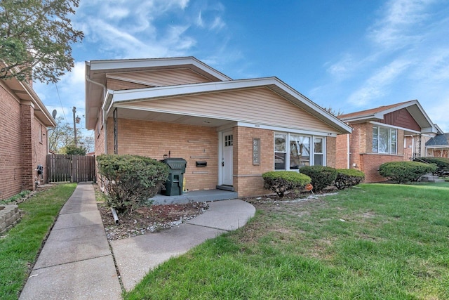 ranch-style home with a gate, a front lawn, brick siding, and fence