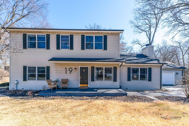 traditional-style home with a front lawn, a chimney, and covered porch