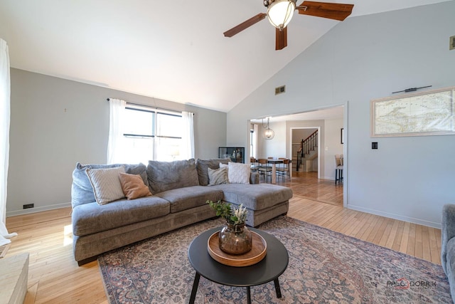 living area featuring stairway, visible vents, light wood finished floors, and a ceiling fan