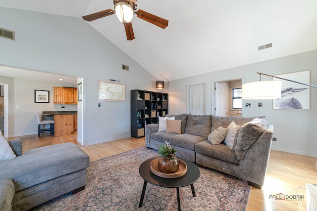 living area featuring high vaulted ceiling, ceiling fan, light wood-style floors, and visible vents