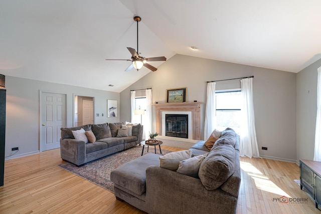 living room with ceiling fan, baseboards, a glass covered fireplace, and light wood finished floors