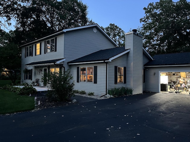 view of front of property featuring a chimney and aphalt driveway