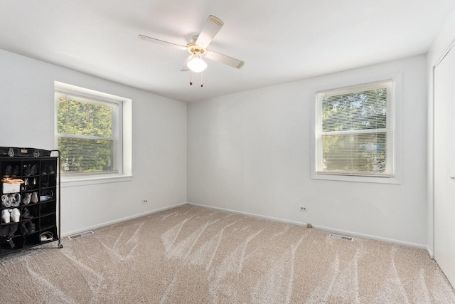 carpeted empty room featuring visible vents, baseboards, and ceiling fan