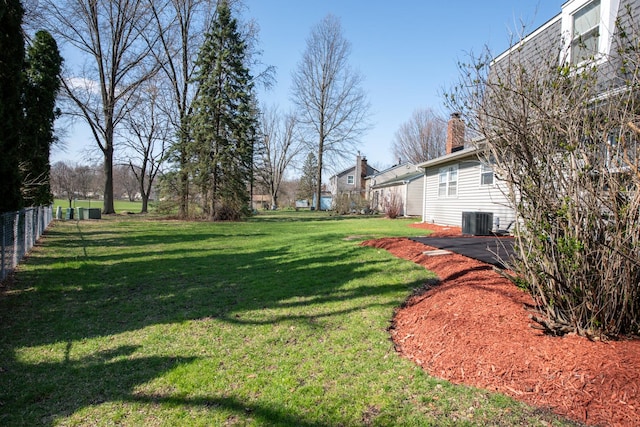 view of yard with central AC and fence