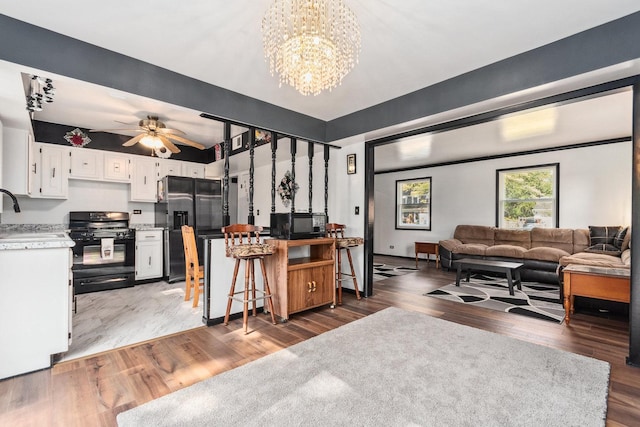 living room featuring ceiling fan with notable chandelier and wood finished floors