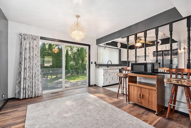 interior space with tasteful backsplash, black microwave, light countertops, pendant lighting, and wood finished floors
