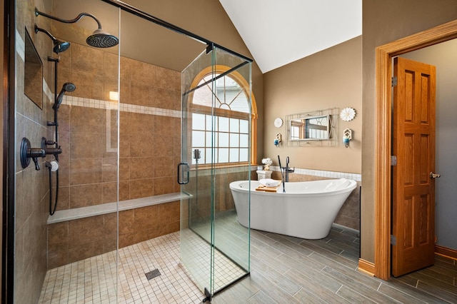 bathroom featuring a shower stall, a freestanding bath, and vaulted ceiling
