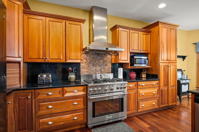 kitchen with brown cabinetry, stainless steel appliances, dark wood-type flooring, and wall chimney exhaust hood
