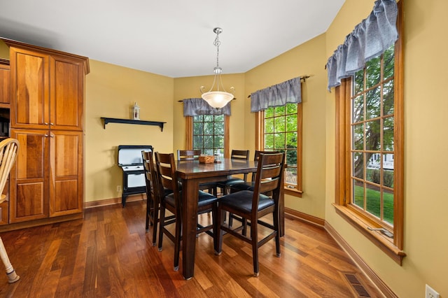dining space featuring visible vents, dark wood-style flooring, and baseboards