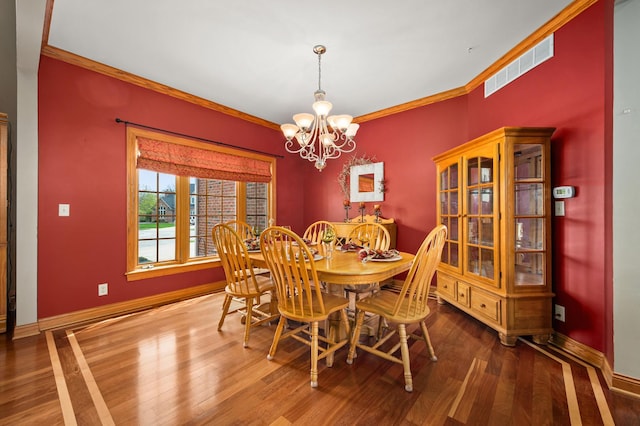 dining area featuring visible vents, a chandelier, crown molding, and wood finished floors