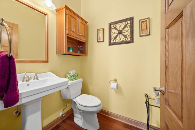 half bathroom featuring toilet, wood finished floors, and baseboards
