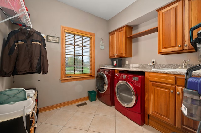 laundry area featuring light tile patterned floors, a sink, cabinet space, washing machine and clothes dryer, and visible vents