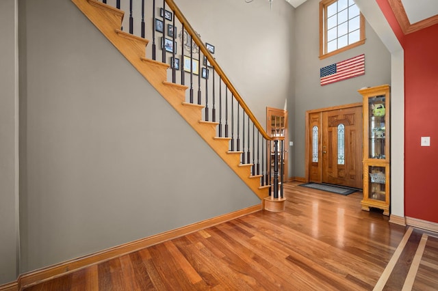 entrance foyer with wood finished floors, baseboards, a high ceiling, and stairs