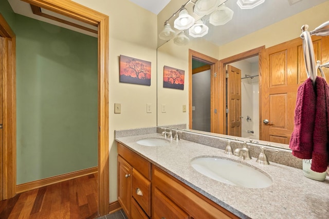 bathroom featuring a sink, double vanity, a shower, and wood finished floors