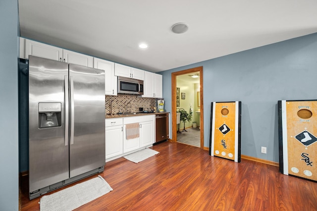 kitchen featuring white cabinets, appliances with stainless steel finishes, dark wood-type flooring, and tasteful backsplash
