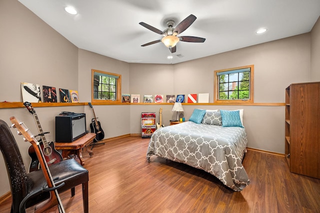 bedroom with multiple windows, wood finished floors, and baseboards