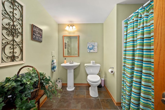 full bathroom featuring a notable chandelier, baseboards, toilet, a shower with shower curtain, and tile patterned floors