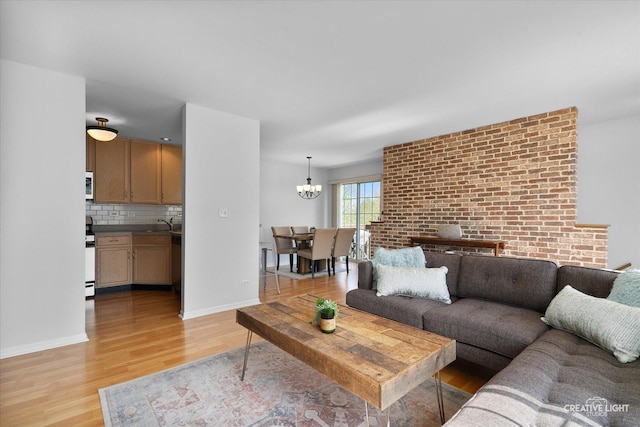 living area with light wood-type flooring, a chandelier, and baseboards