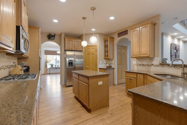 kitchen with arched walkways, appliances with stainless steel finishes, a sink, tasteful backsplash, and recessed lighting