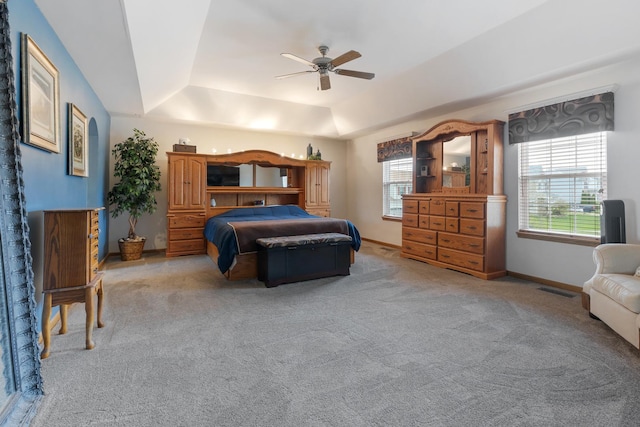 bedroom with a raised ceiling, light carpet, ceiling fan, and baseboards
