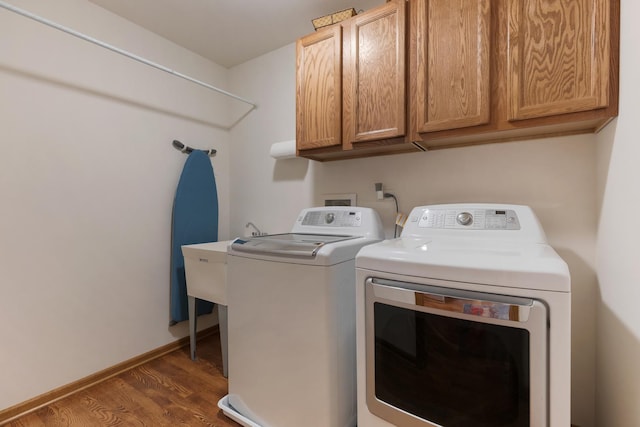 clothes washing area with washing machine and dryer, cabinet space, dark wood-style flooring, and baseboards