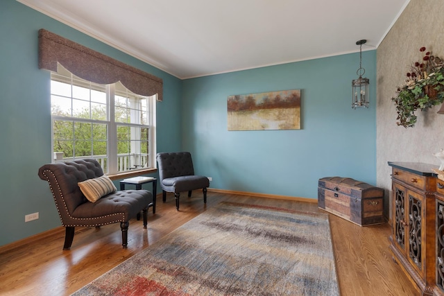 sitting room featuring ornamental molding, wood finished floors, and baseboards