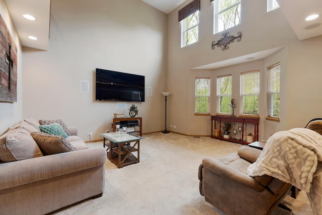 living area featuring light carpet, a high ceiling, recessed lighting, and baseboards
