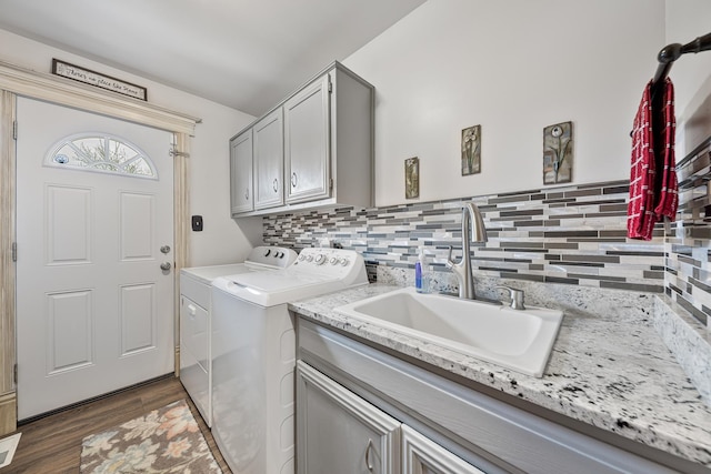 laundry room featuring wood finished floors, washing machine and clothes dryer, a sink, and cabinet space