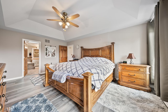 bedroom with visible vents, baseboards, a raised ceiling, and light wood-type flooring