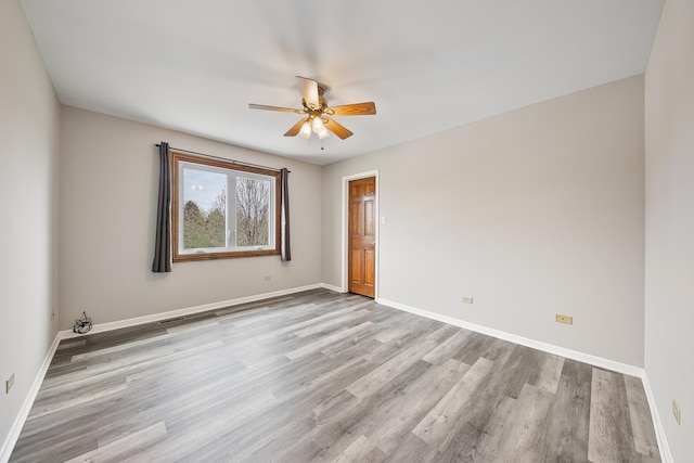 unfurnished room with wood finished floors, ceiling fan, and baseboards