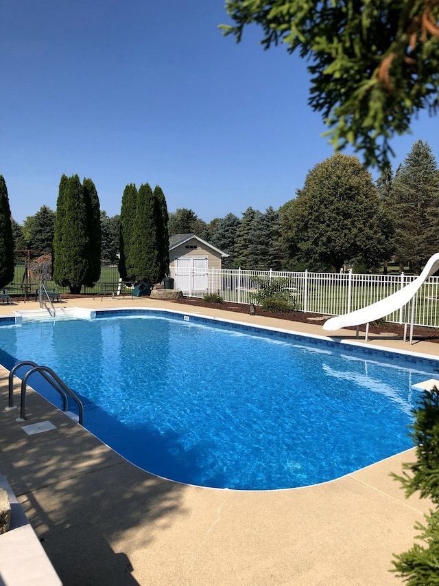 view of swimming pool with fence, a water slide, a fenced in pool, and a patio