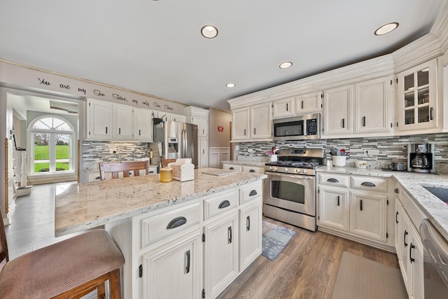 kitchen with a center island, wood finished floors, backsplash, and stainless steel appliances
