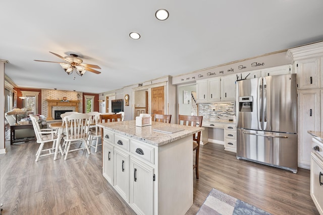 kitchen with a breakfast bar, a ceiling fan, white cabinetry, and stainless steel fridge
