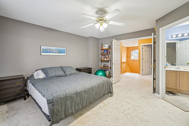 bedroom featuring ceiling fan, light colored carpet, and ensuite bath