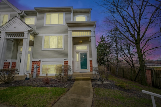 view of property featuring brick siding and fence