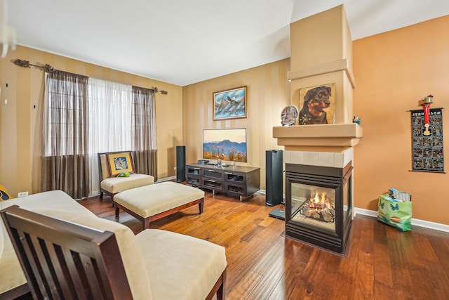 living area featuring baseboards, a multi sided fireplace, and hardwood / wood-style flooring