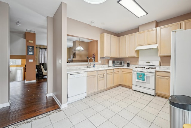 kitchen featuring light brown cabinets, white appliances, light countertops, under cabinet range hood, and a sink