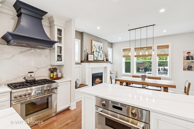 10044 S Leavitt St, Chicago, IL 60643 - kitchen with appliances with stainless steel finishes, custom exhaust hood, a tiled fireplace, light wood-type flooring, and white cabinetry