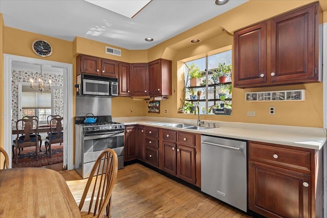 kitchen with an inviting chandelier, light wood-type flooring, visible vents, appliances with stainless steel finishes, and a sink